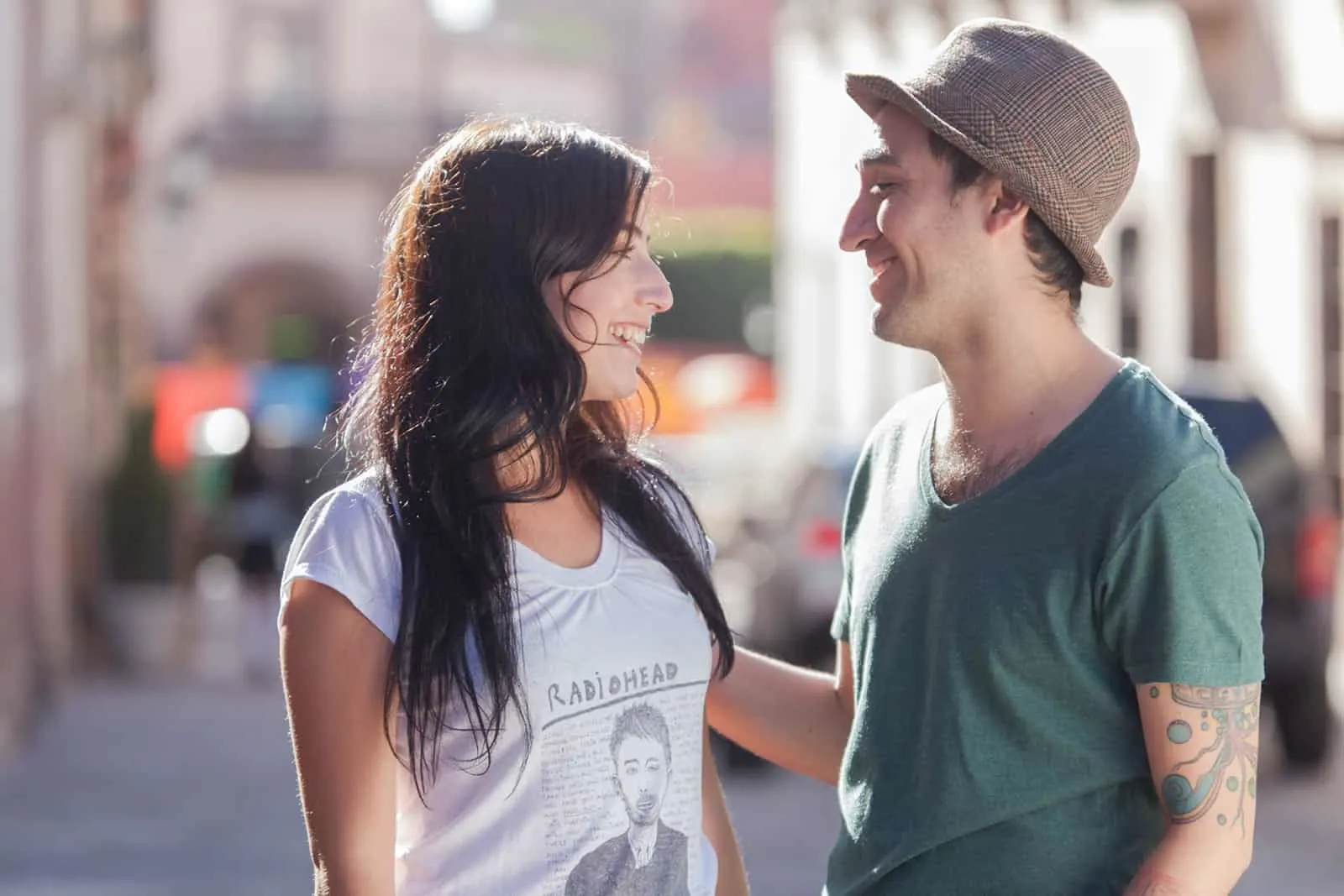Ein lächelnder Mann berührt eine Schulter einer Frau, die auf einer Straße in seiner Nähe steht