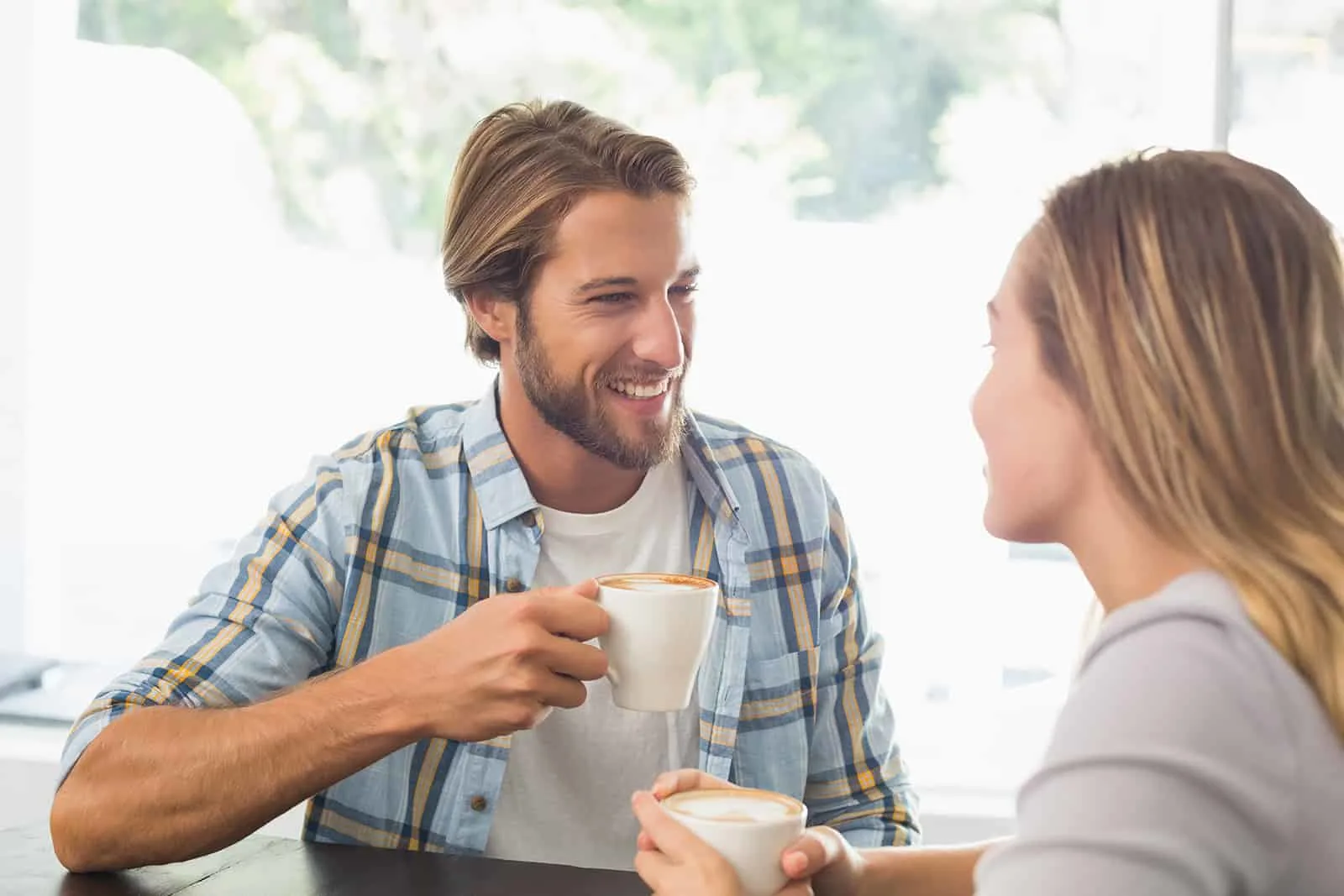 Ein lächelnder Mann trinkt Kaffee mit einer Frau bei einem Date