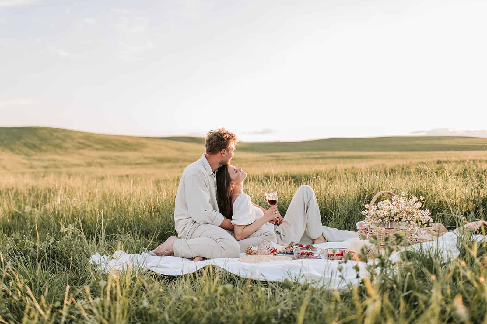 Ein liebevolles Paar, das ein Picknick auf der weißen Matte auf dem Feld hat