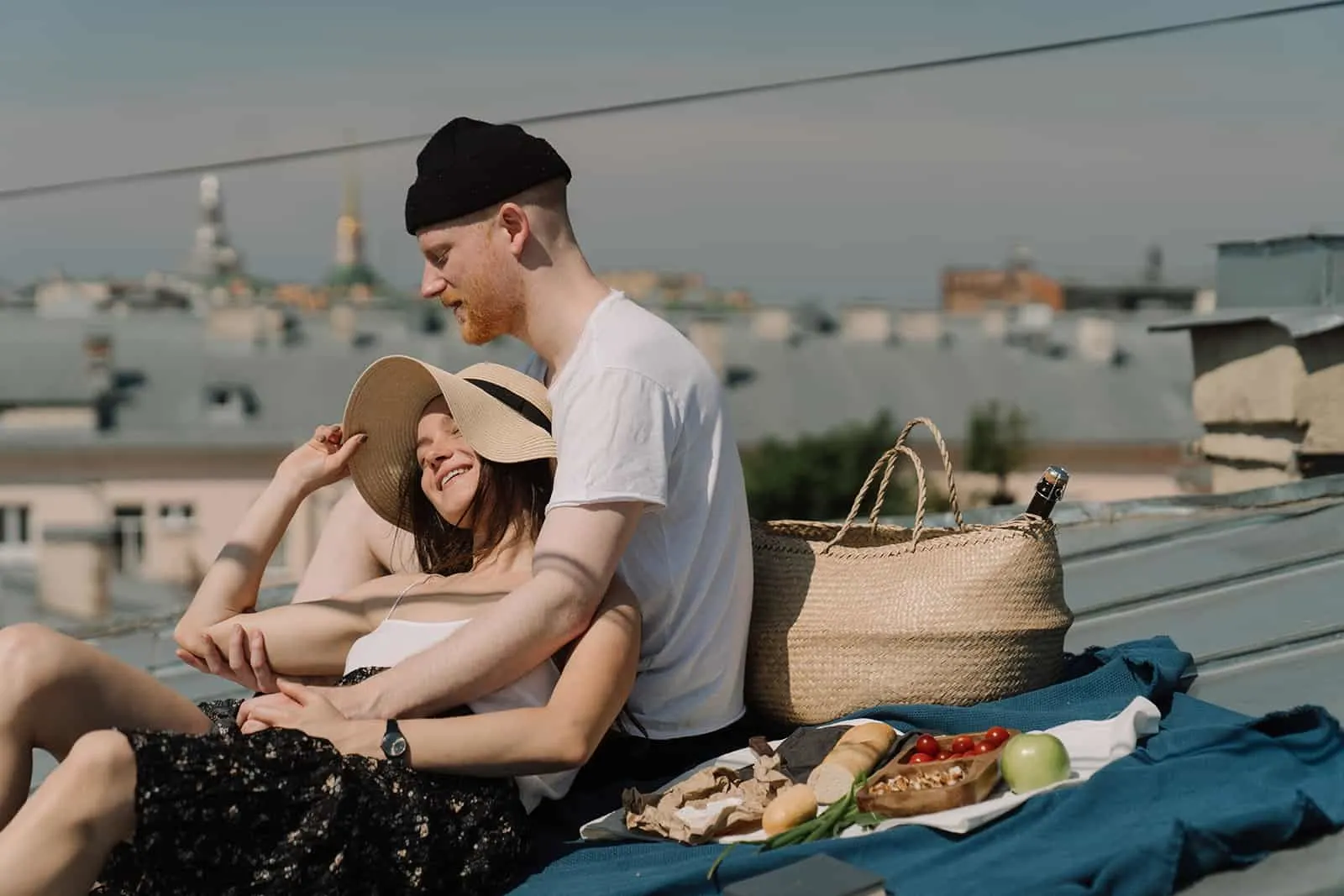 ein liebendes Paar, das ein Picknick auf einer blauen Matte auf dem Dach sitzt