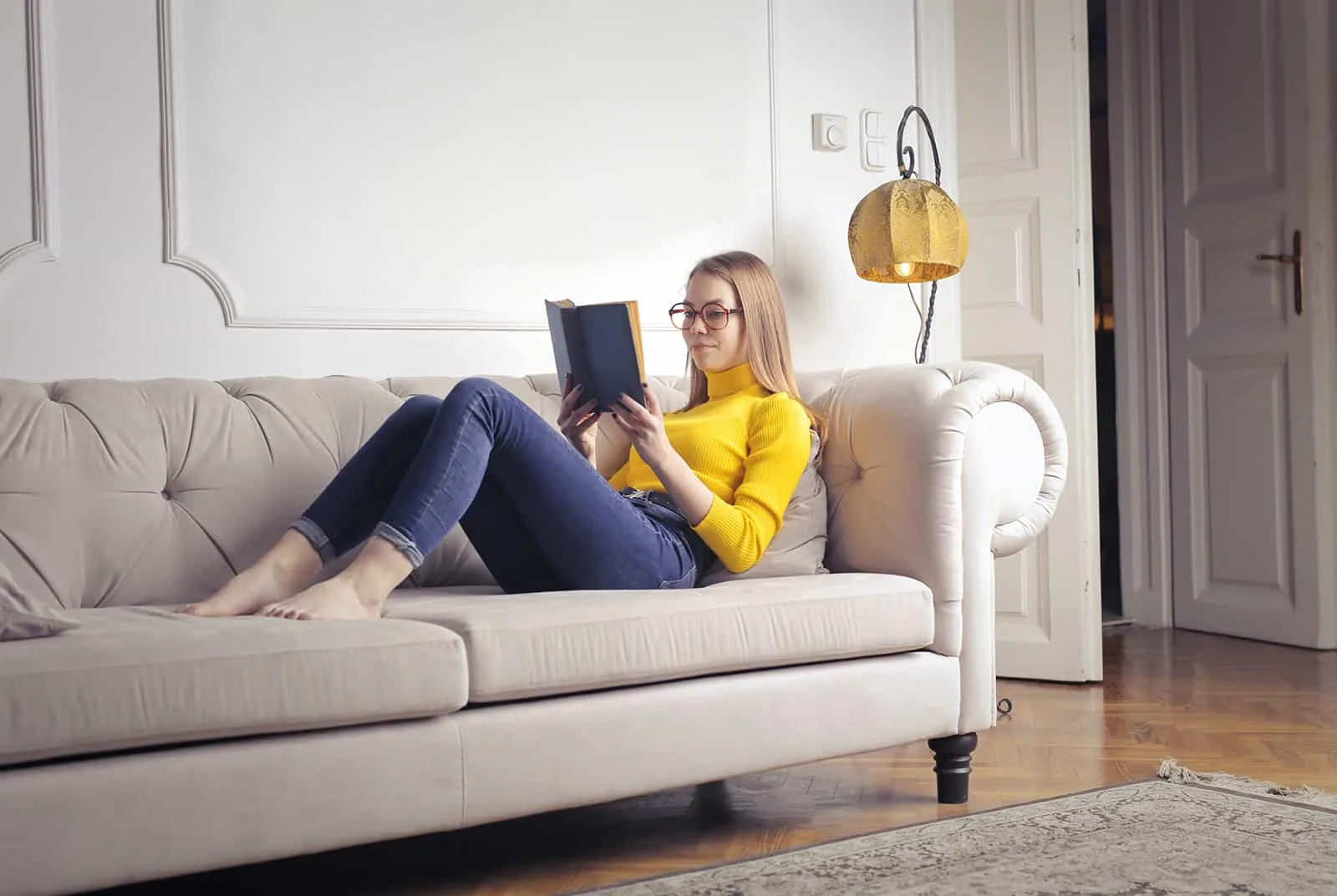 eine Frau, die ein Buch liest, das auf der Couch sitzt
