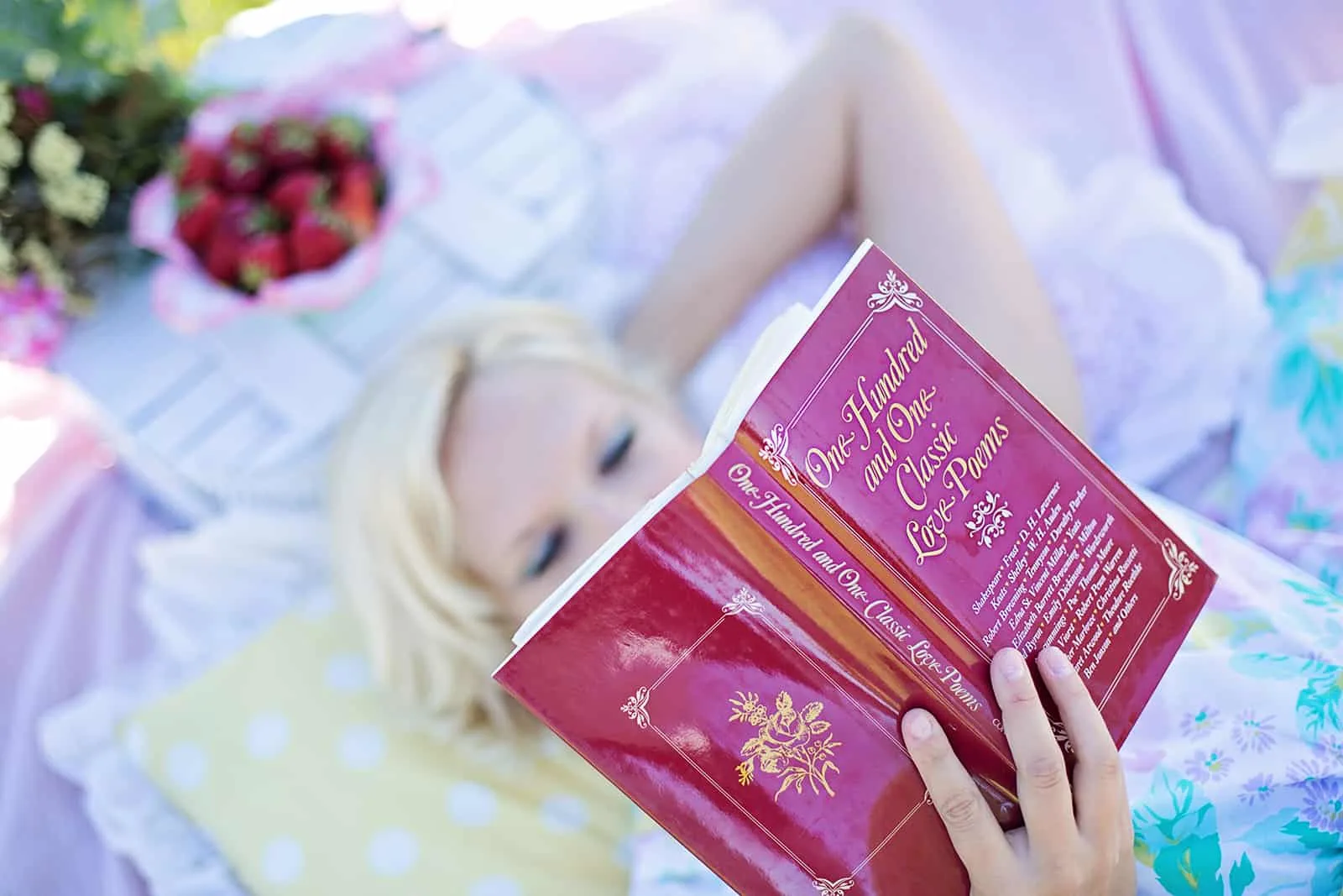 eine Frau, die ein Buch mit Liebesgedichten liest, während sie auf der Decke liegt