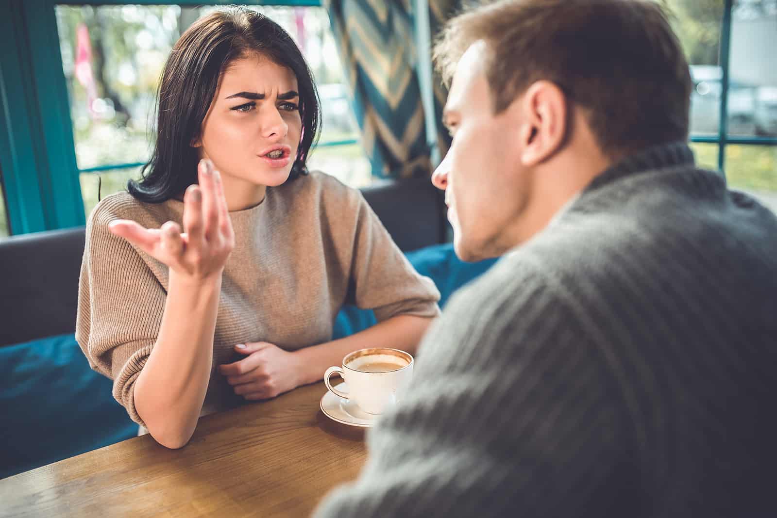 Eine Frau spricht mit einem Mann, der mit ihr im Café Kaffee trinkt, über ihre Probleme