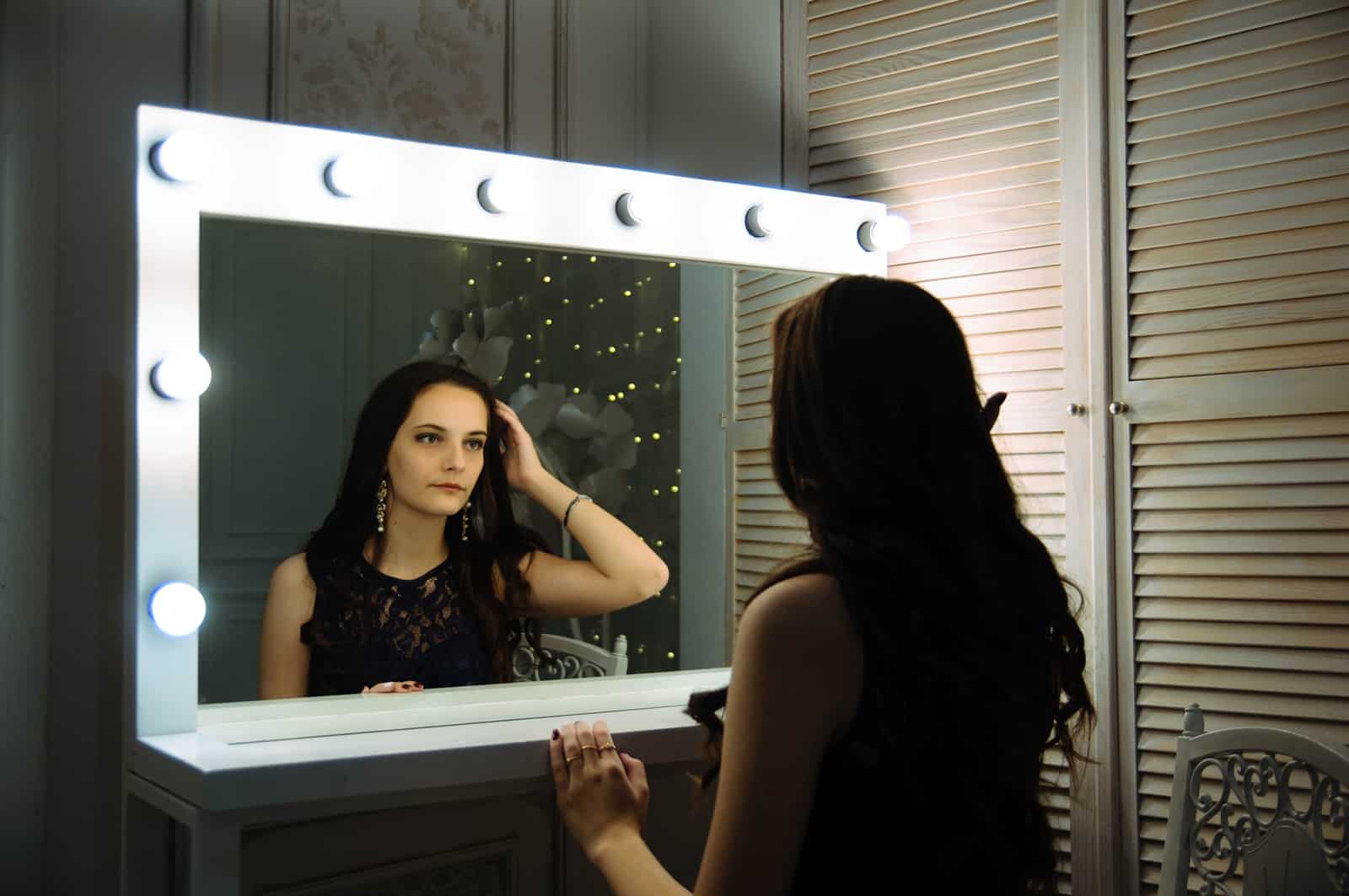 eine Frau, die sich beim Nachdenken in den Spiegel schaut