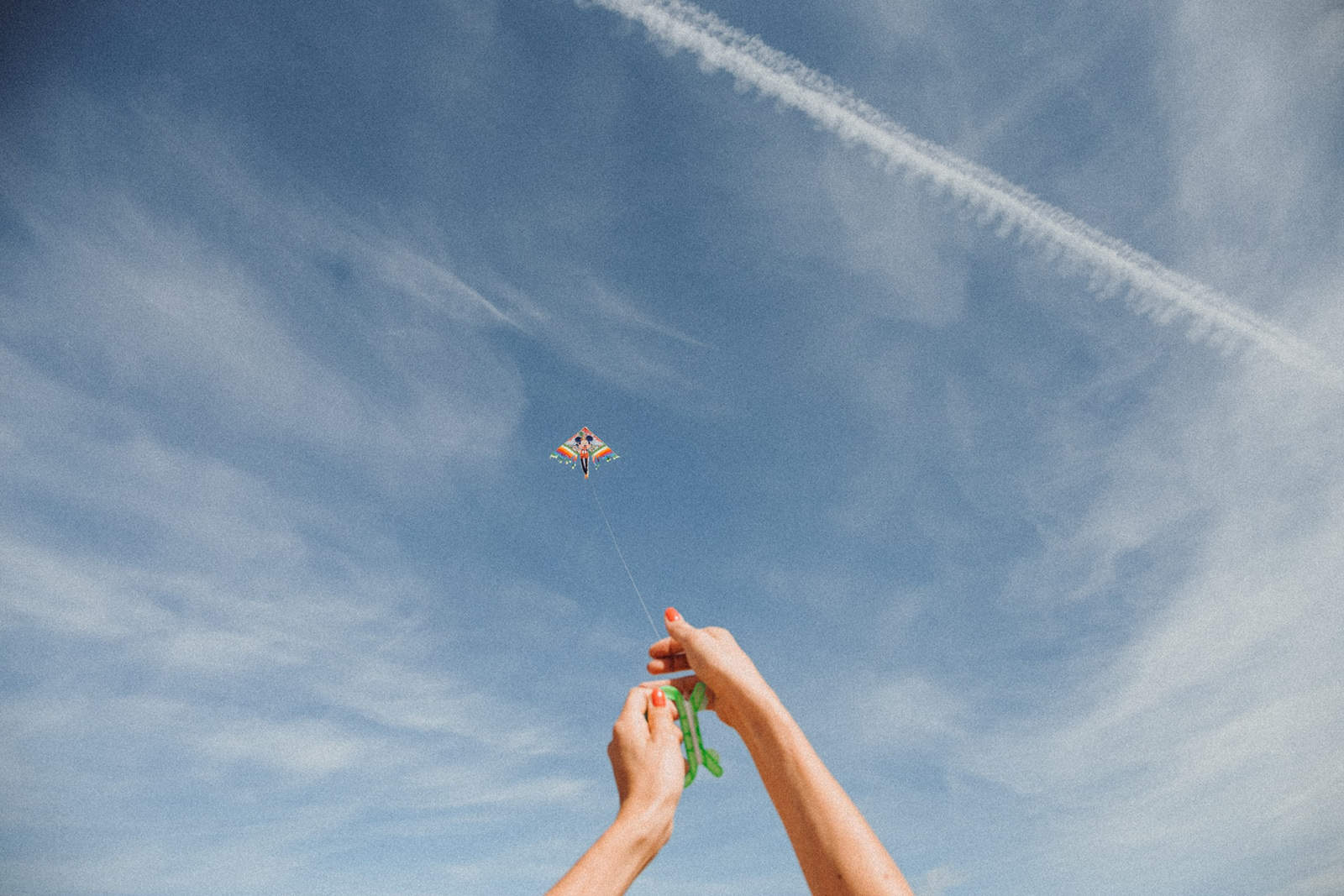 Eine Frau, die einen Drachen am sonnigen Tag hält