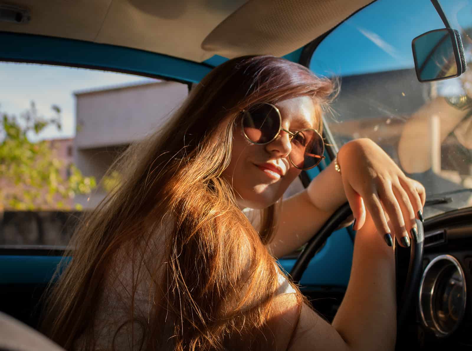 Eine Frau mit langen Haaren sitzt im Auto und lehnt den Kopf am Lenkrad