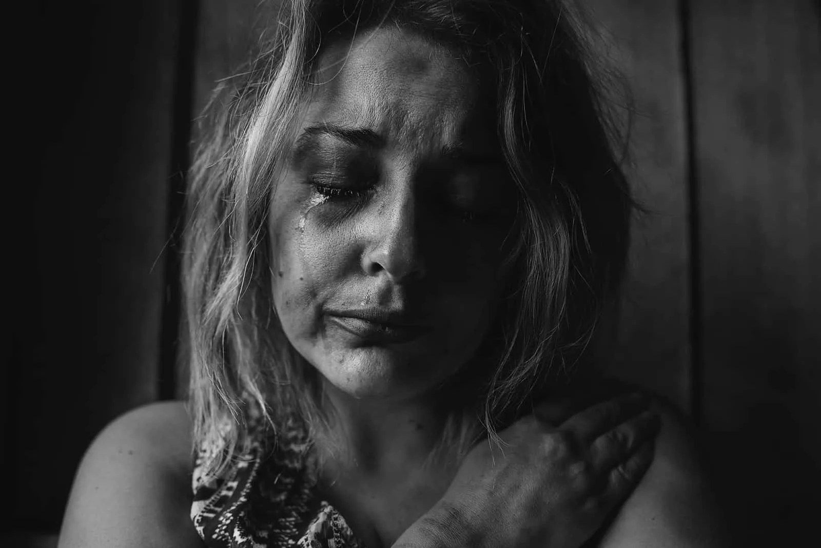 eine depressive Frau, die mit geschlossenen Augen weint