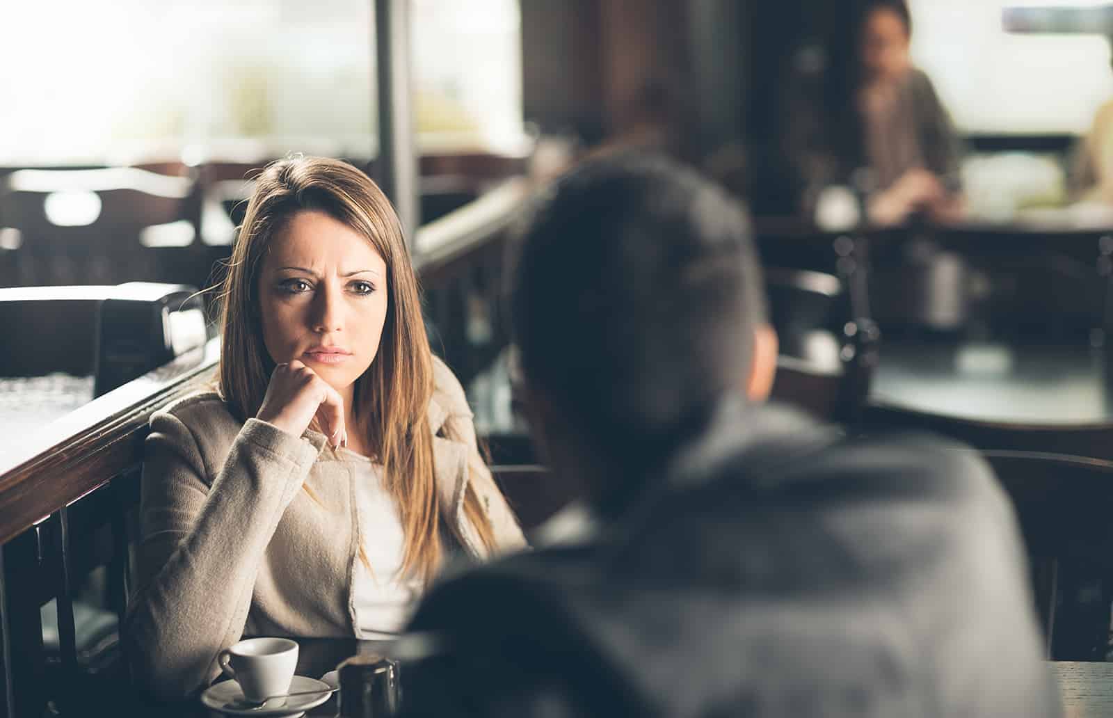 eine ernste Frau, die mit einem Mann im Café auf einem Date sitzt