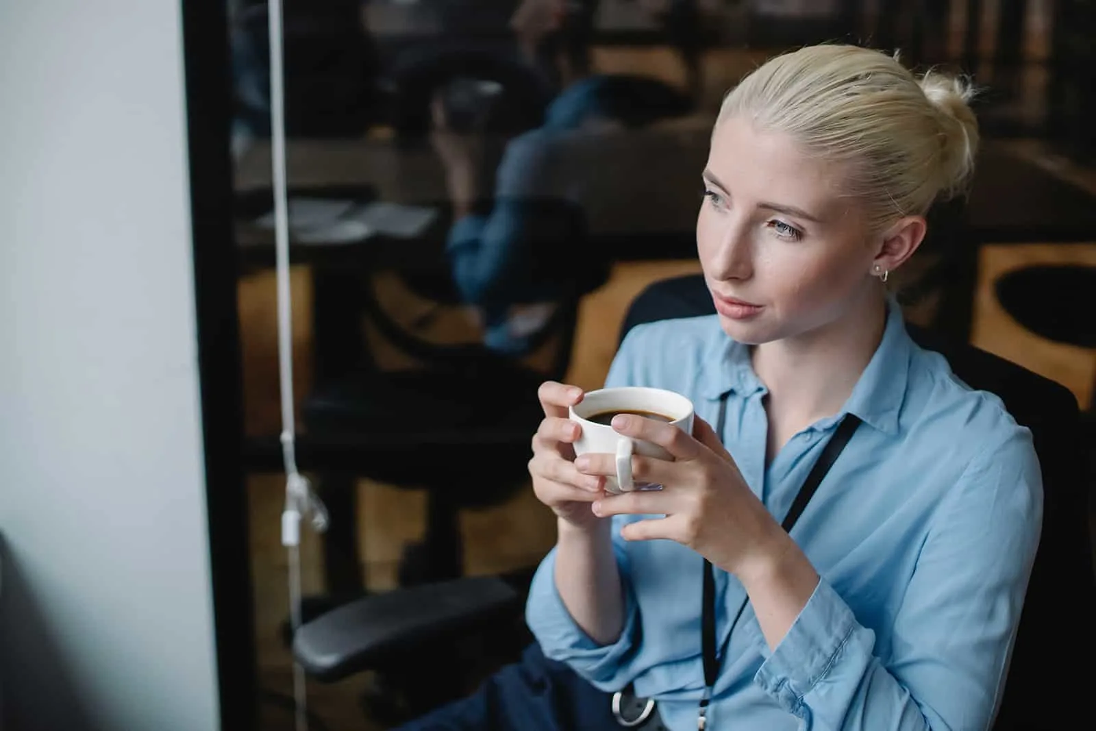 nachdenkliche Frau hält eine Tasse Kaffee im Café sitzen