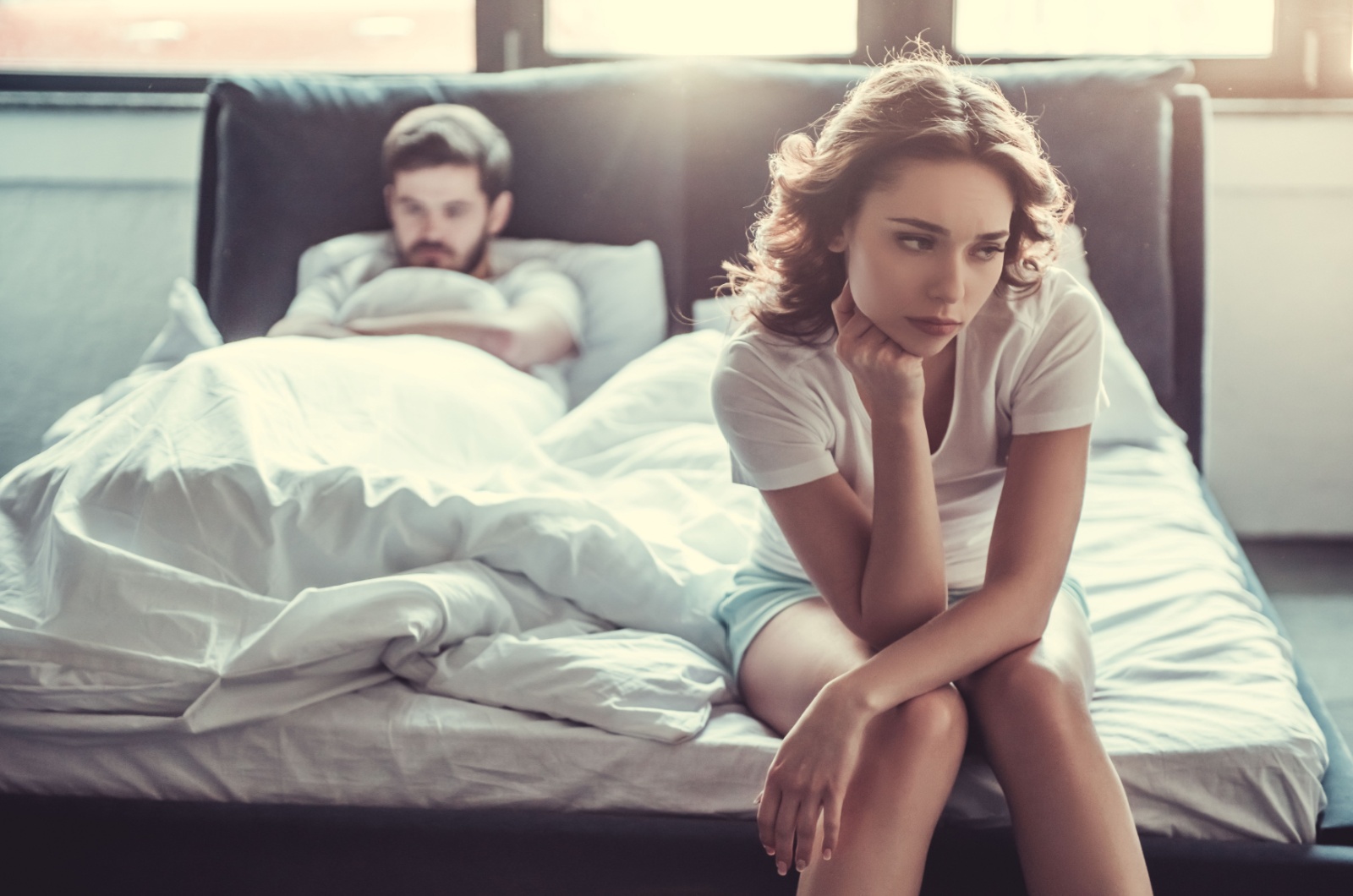 traurige junge Frau sitzt auf dem Bett