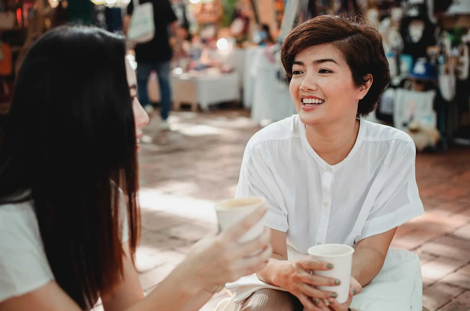 zwei Freundinnen unterhalten sich beim gemeinsamen Kaffeetrinken auf der Straße