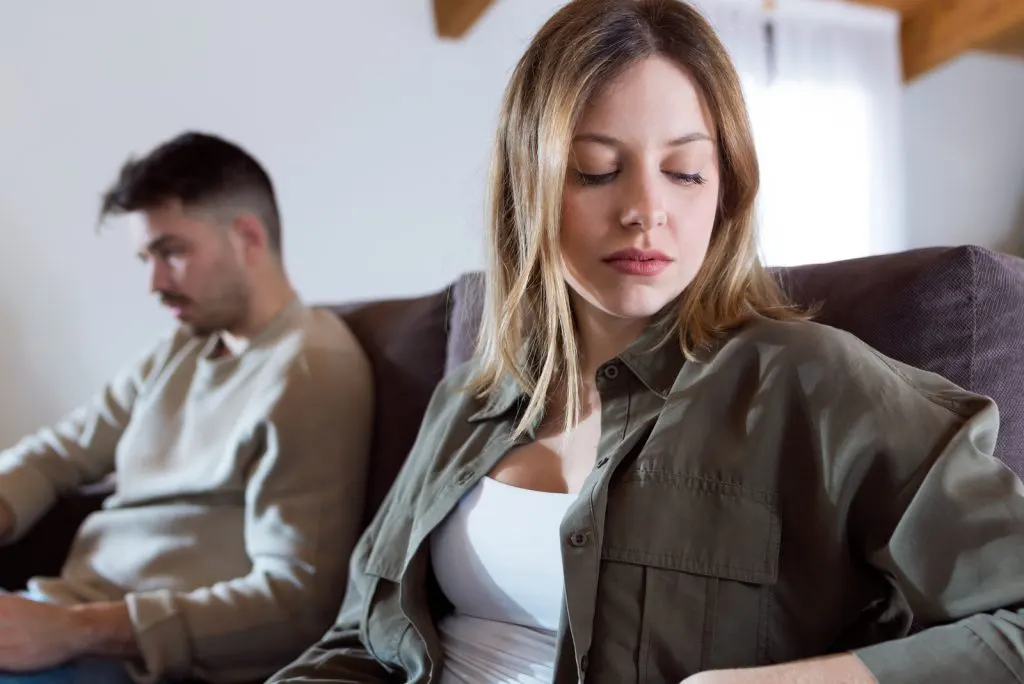 wuetendes junges Paar, das zusammen auf Sofa sitzt