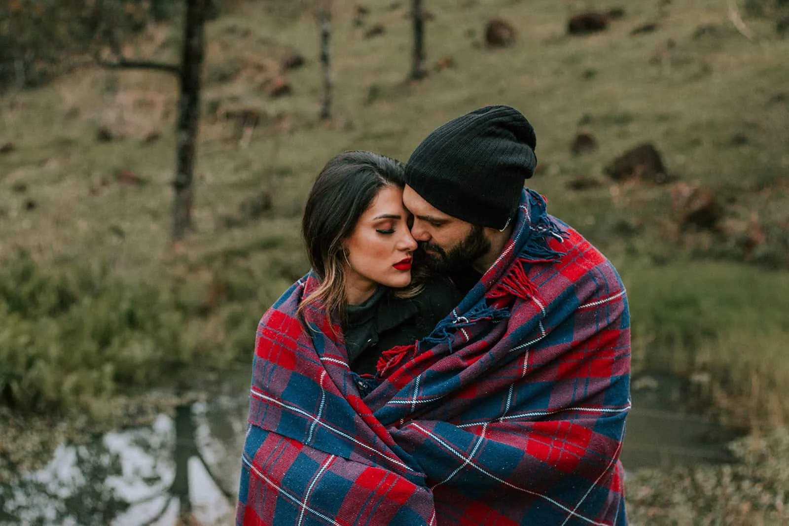 ein liebendes Paar bedeckt mit einer Decke, die in der Natur steht
