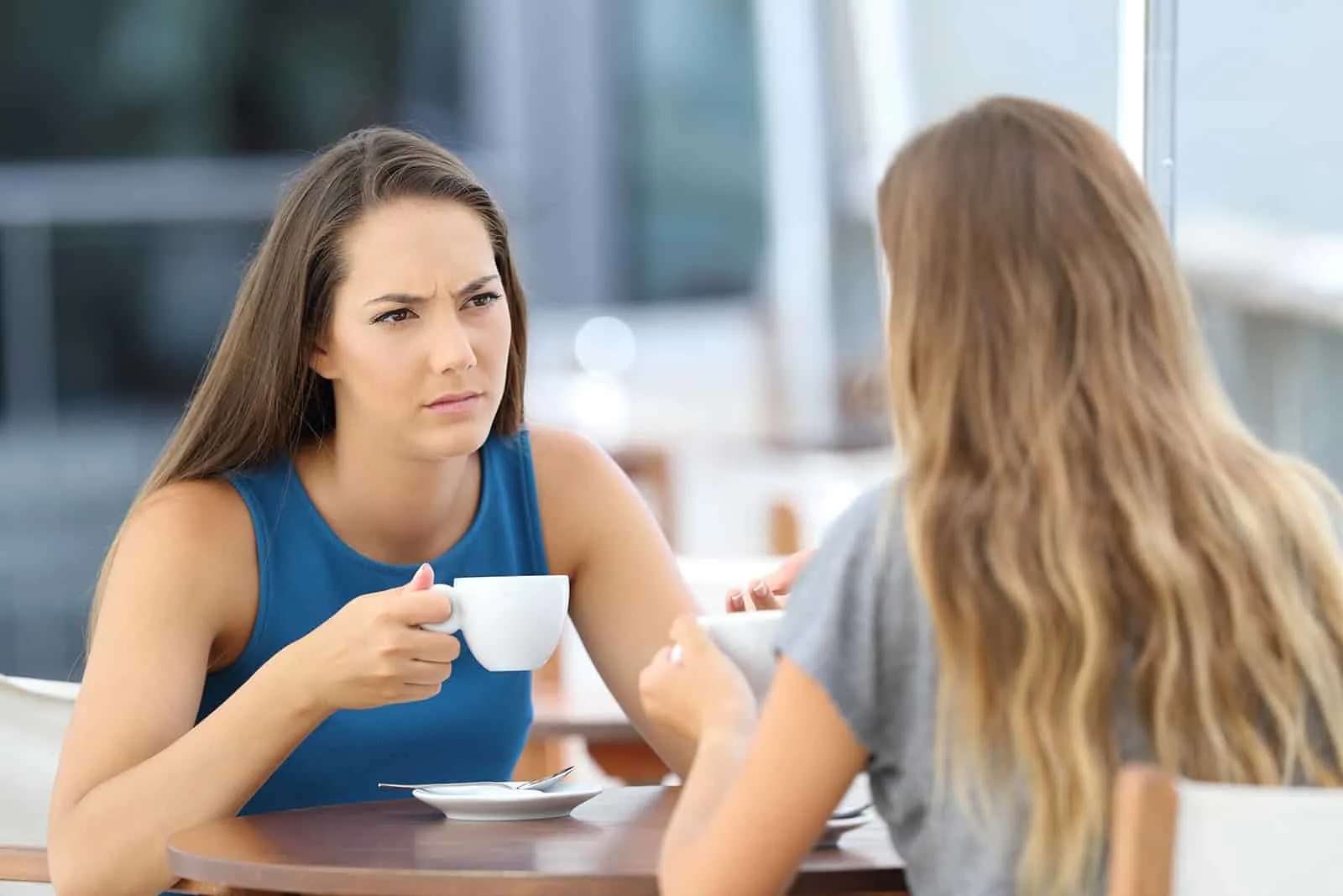 verärgerte Frau, die ihrer Freundin zuhört, die mit ihr im Café sitzt