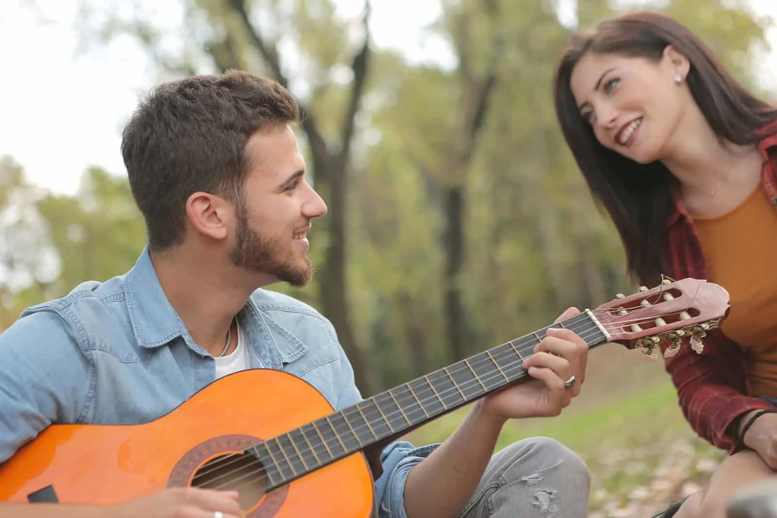 Ein Mann spielt einer lächelnden Frau Gitarre