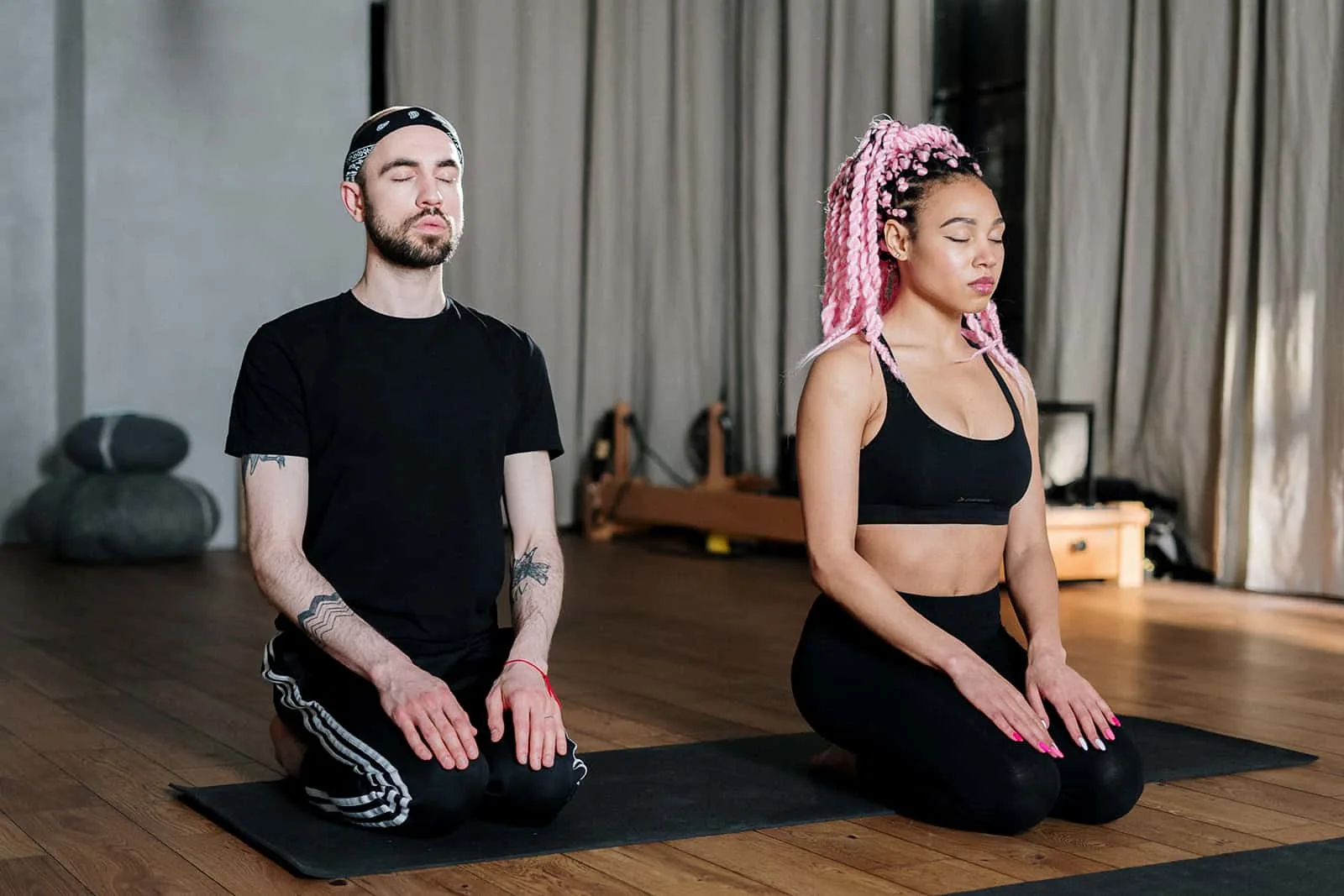 Ein Mann und eine Frau meditieren zusammen auf einer schwarzen Matte