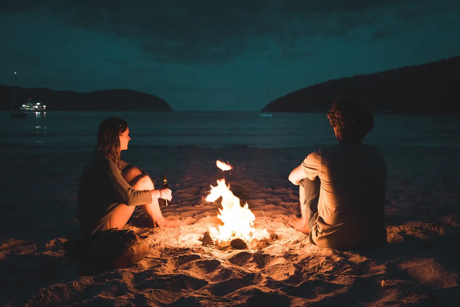 Ein Mann und eine Frau sitzen in der Nähe des Feuers am Strand
