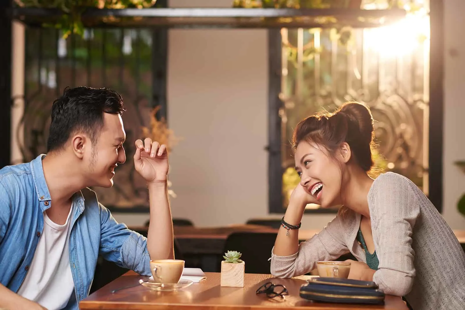 Ein lachender Mann und eine lachende Frau sitzen bei einem Date im Café