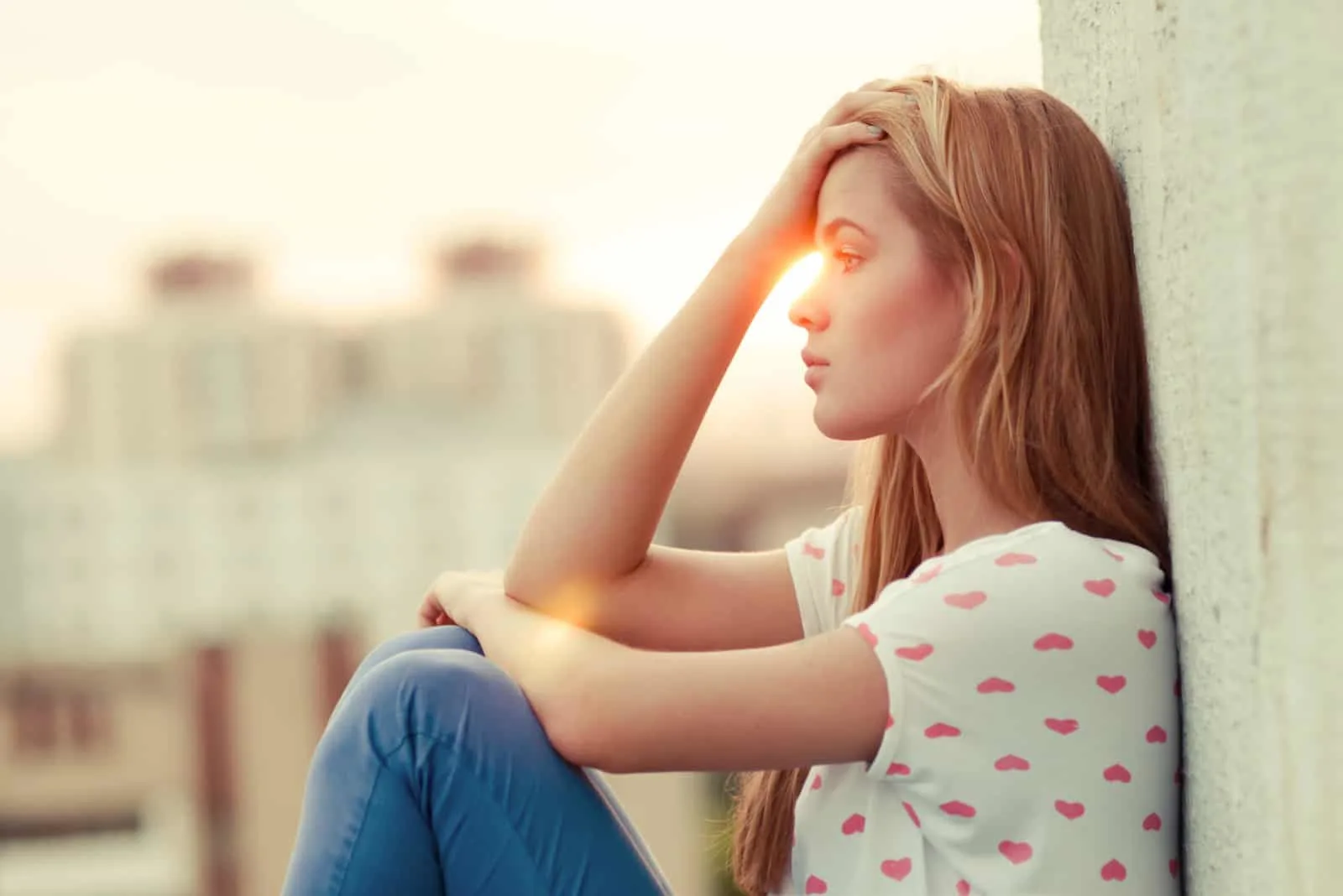 Ein schönes junges Mädchen sitzt auf dem Dach eines Gebäudes
