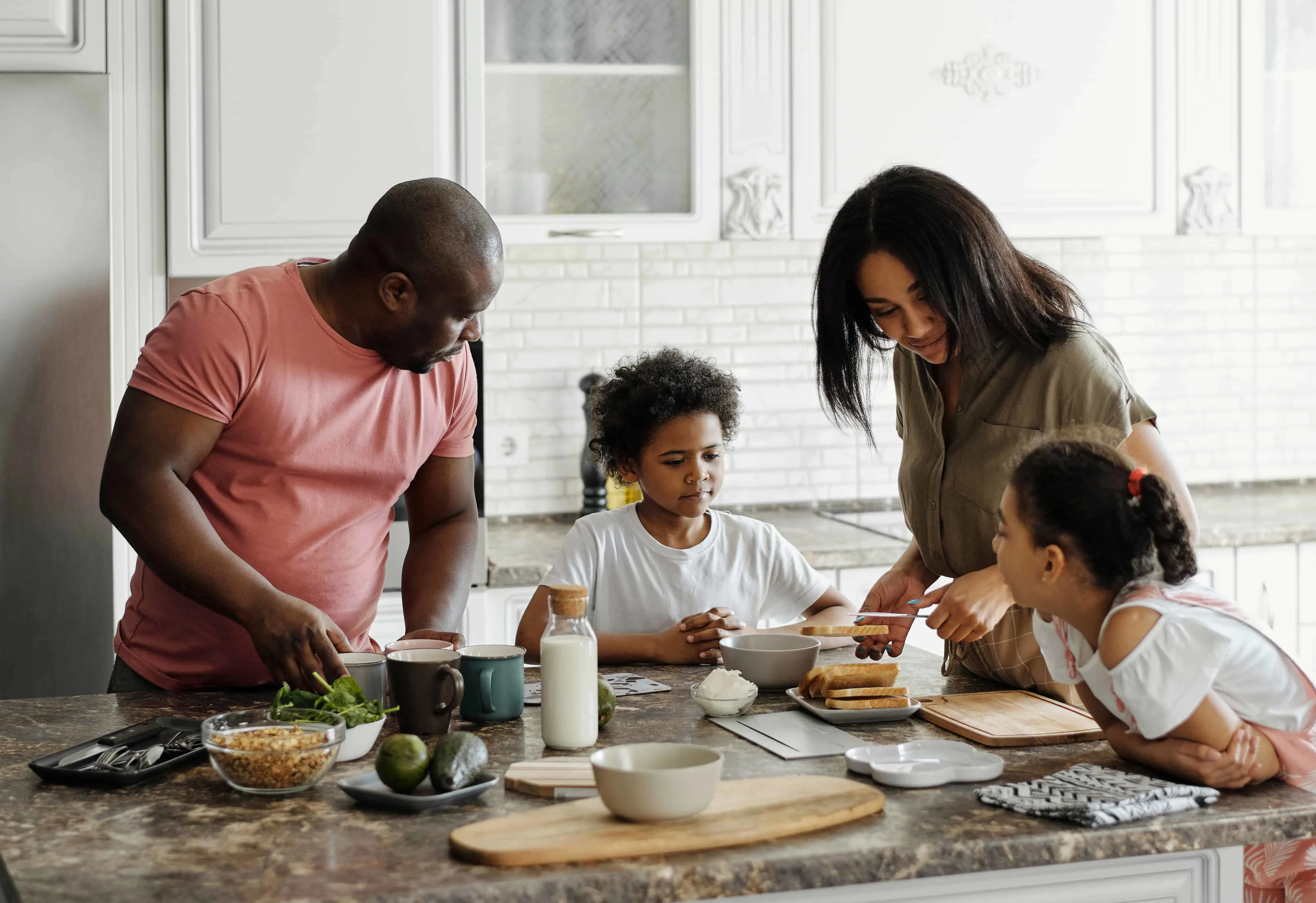 Eltern bereiten mit ihren Kindern das Frühstück in der Küche vor
