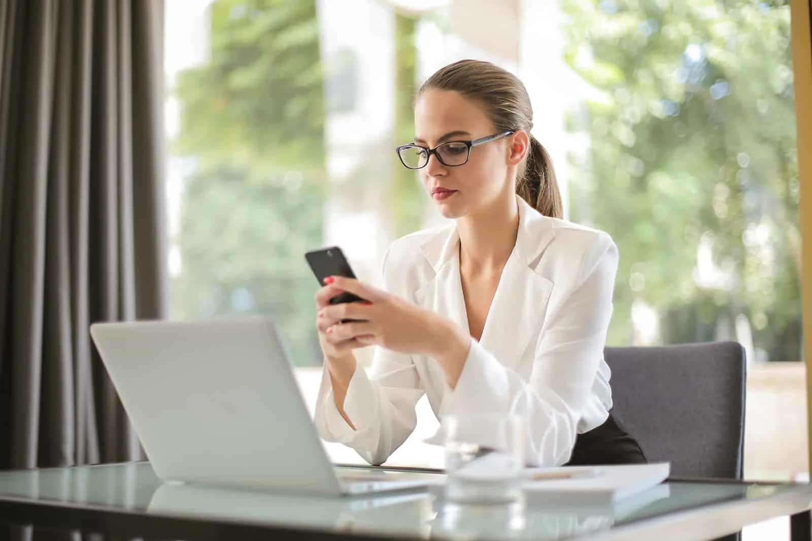 Geschäftsfrau mit ihrem Smartphone im Büro sitzen