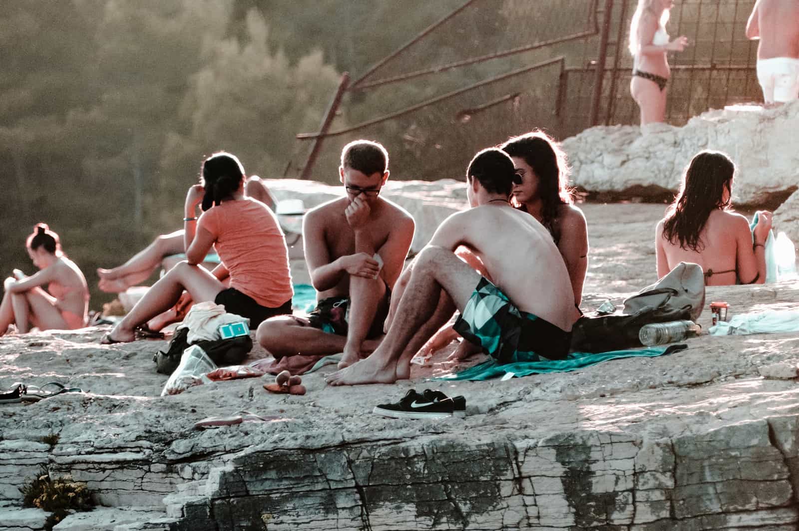 Gruppe von Freunden, die auf den Felsen am Strand sitzen