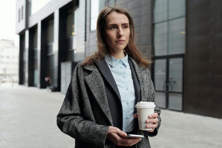 eine Frau, die mit Kaffee in der Hand geht
