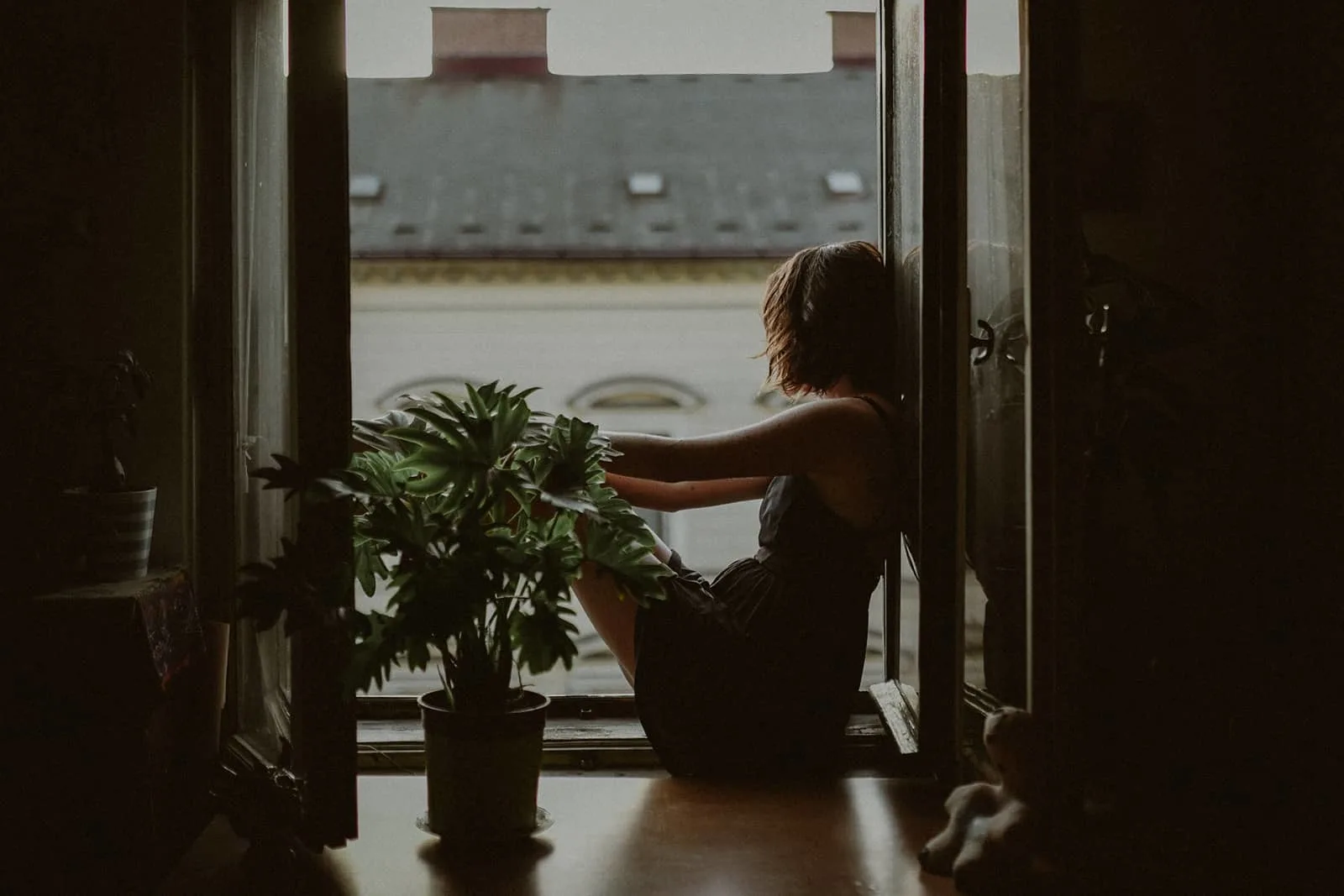 Eine Frau sitzt auf der Fensterbank in ihrer Wohnung