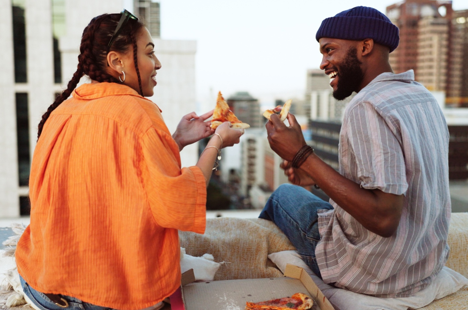 Mann und Frau essen Pizza auf dem Dach
