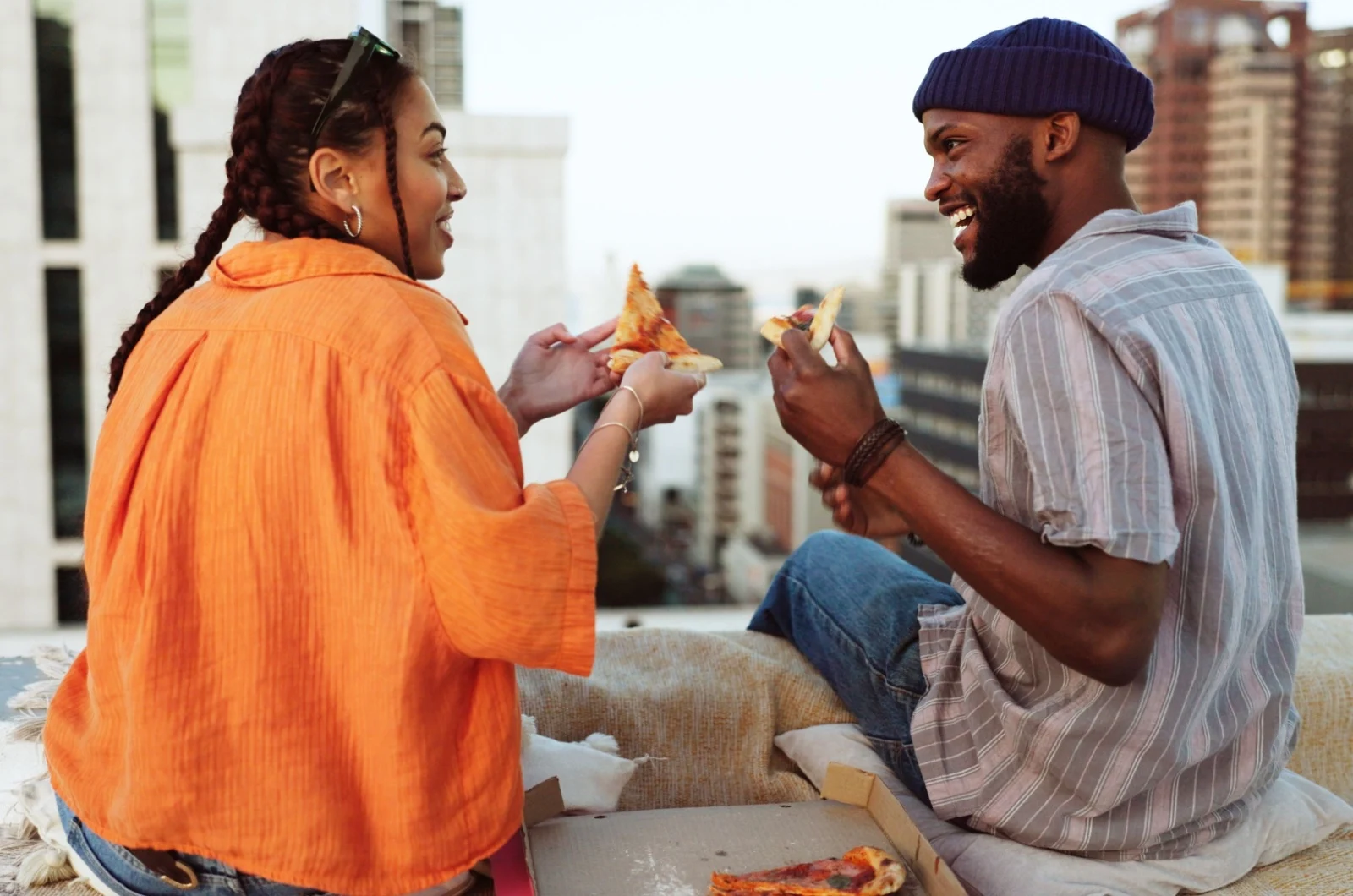 Mann und Frau essen Pizza auf dem Dach