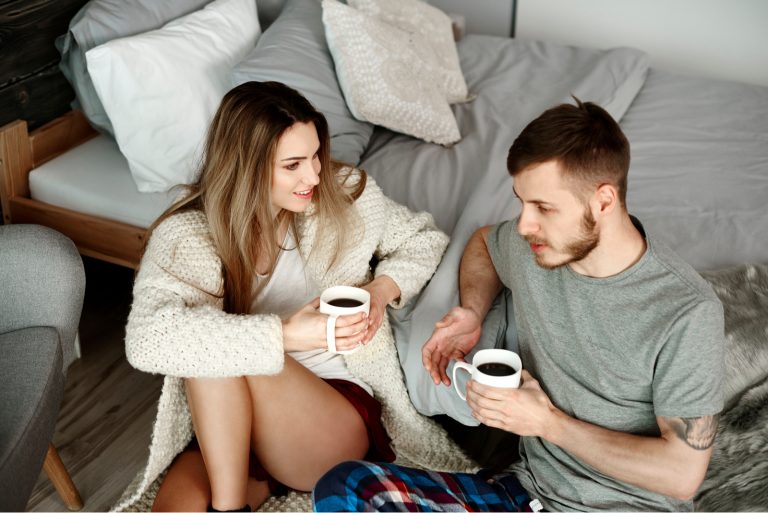 Paar mit Kaffee auf dem Boden sitzen