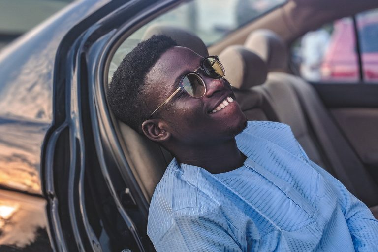 lächelnder Mann, der Sonnenbrille trägt, die im Fahrzeug sitzt