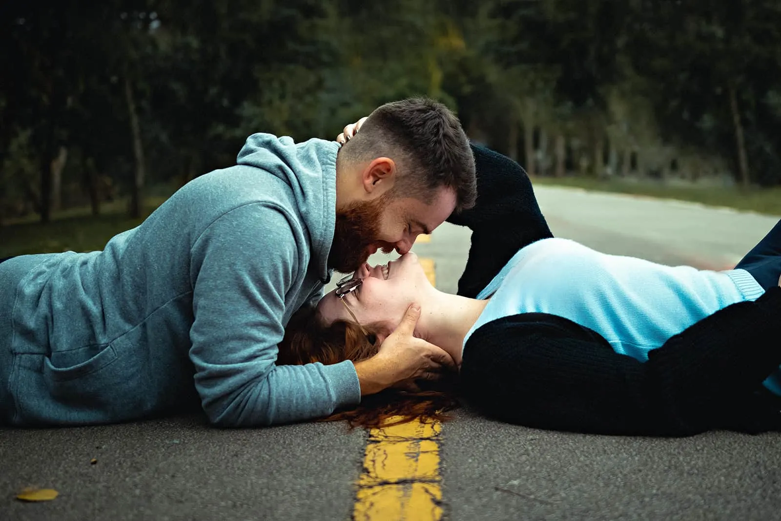 ein Paar, das auf der Asphaltstraße liegt und sich küssen will