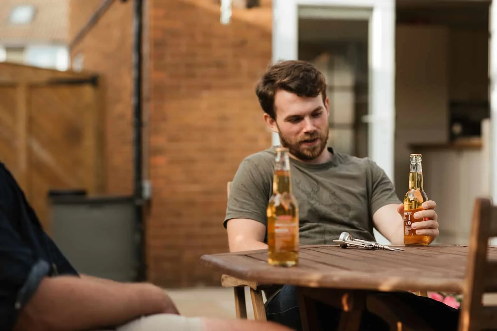 Ein bärtiger Mann, der Bier hält und mit Freunden sitzt
