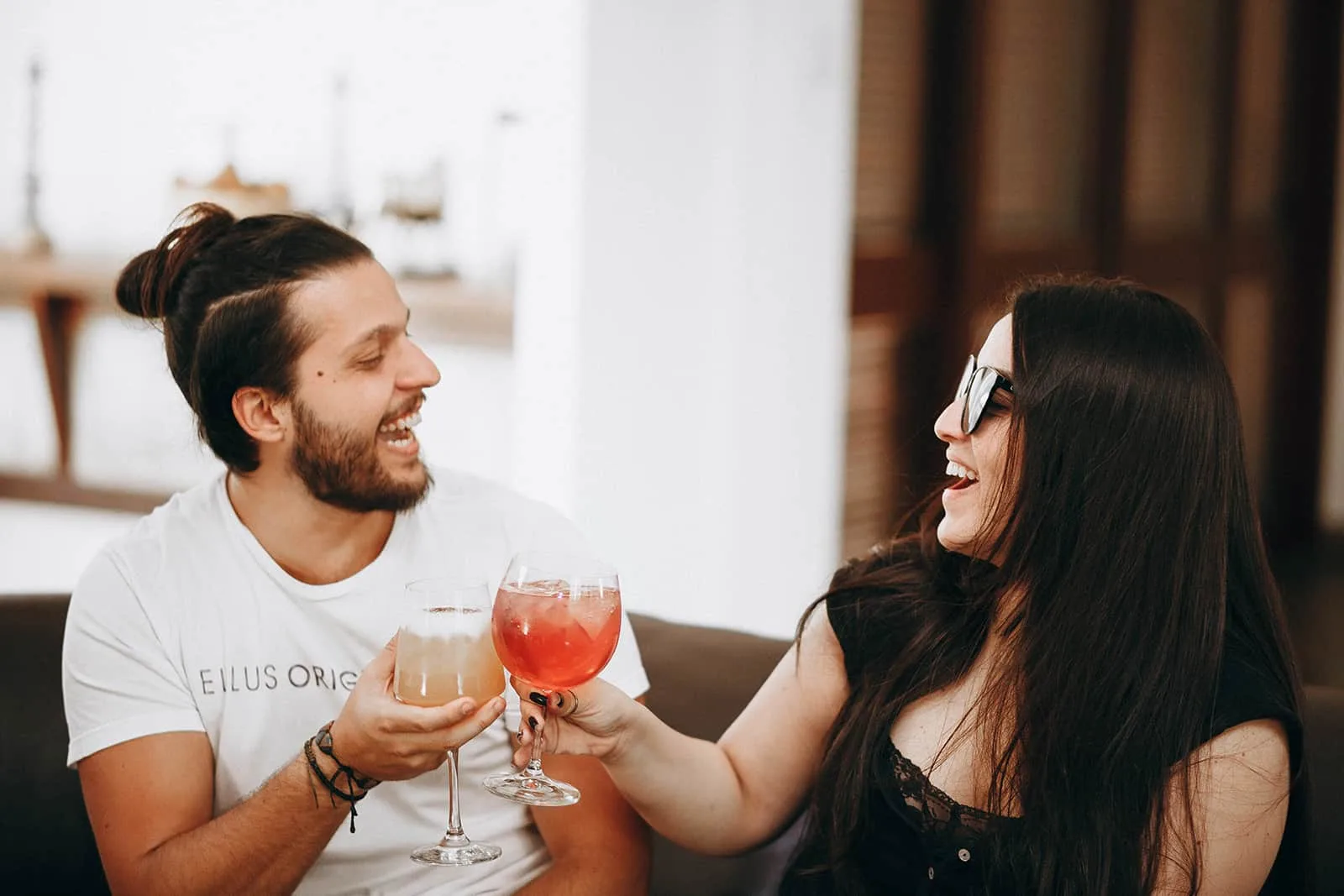 ein fröhlicher Mann und eine fröhliche Frau, die mit Getränken anstoßen und zusammen lachen