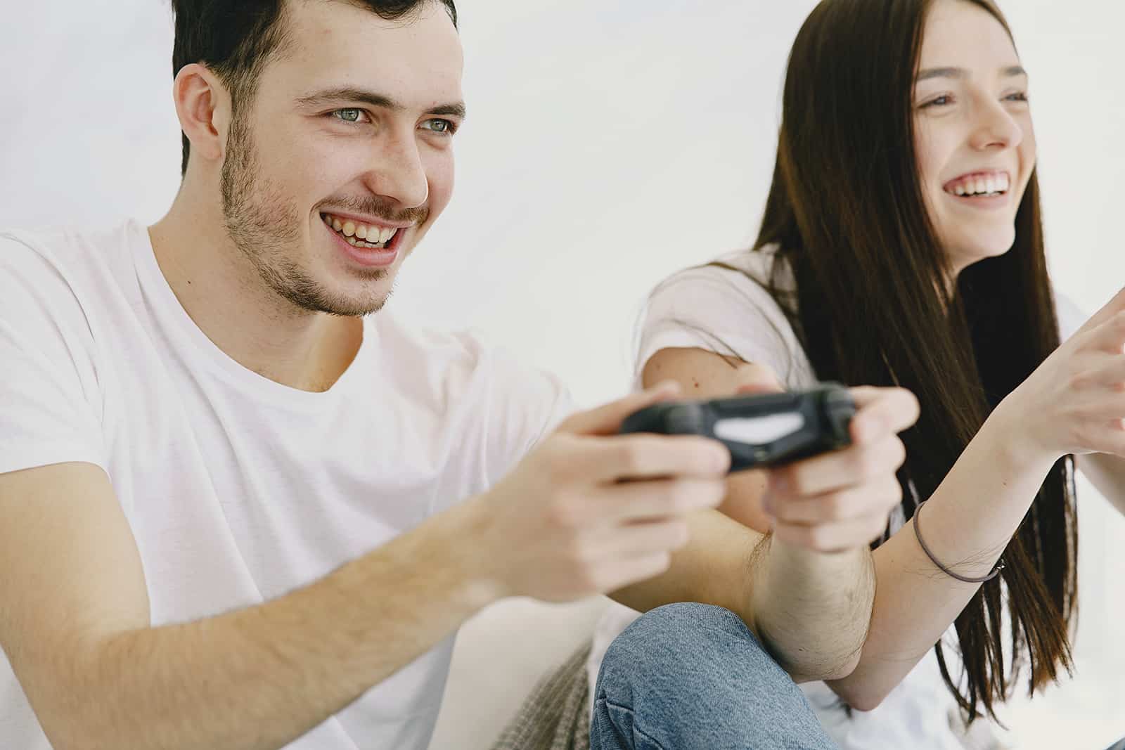 ein lächelnder Mann und eine Frau, die ein Videospiel spielen, das auf der Couch sitzt
