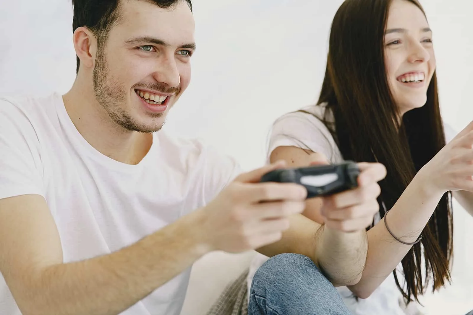 ein lächelnder Mann und eine Frau, die ein Videospiel spielen, das auf der Couch sitzt