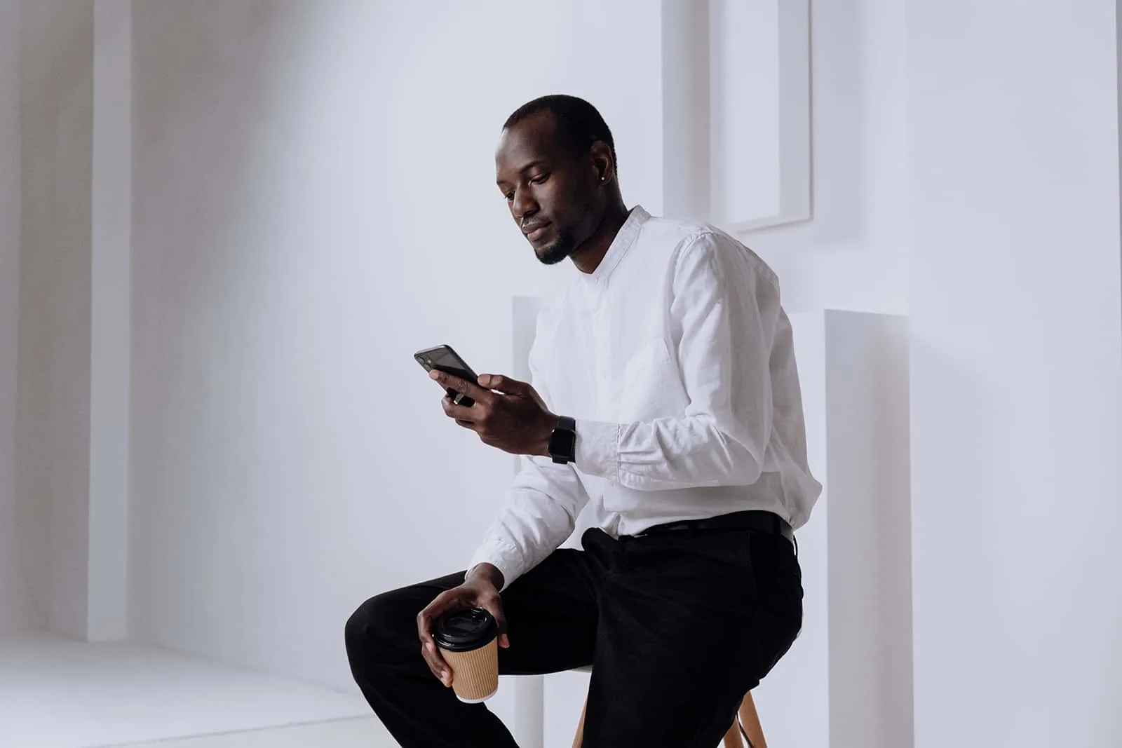 Ein selbstbewusster Mann, der auf seinem Smartphone tippt, während er auf dem Stuhl sitzt