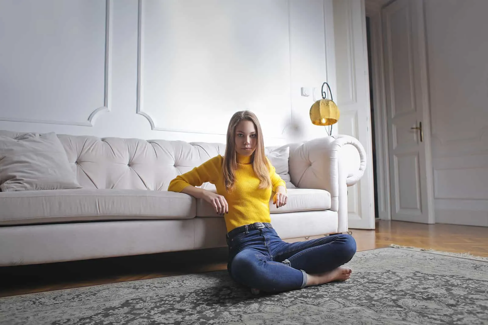 eine junge Frau, die auf dem Boden sitzt und sich auf die Couch lehnt