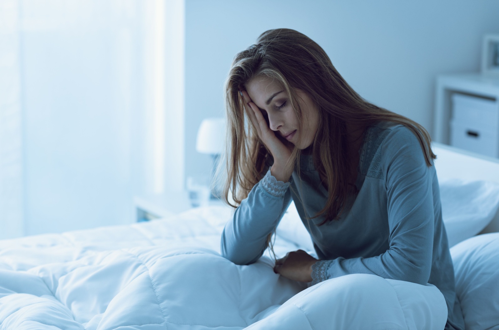 frau sitzt mueede im bett