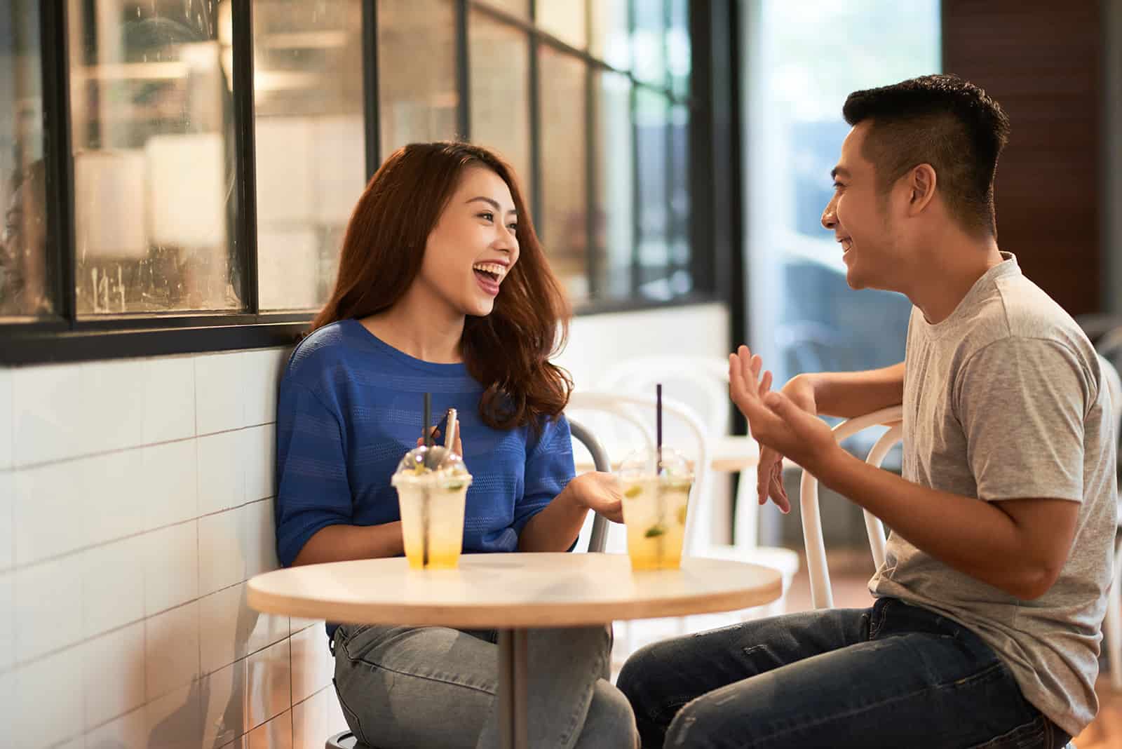lächelnder Mann und Frau sprechen, während sie im Café sitzen