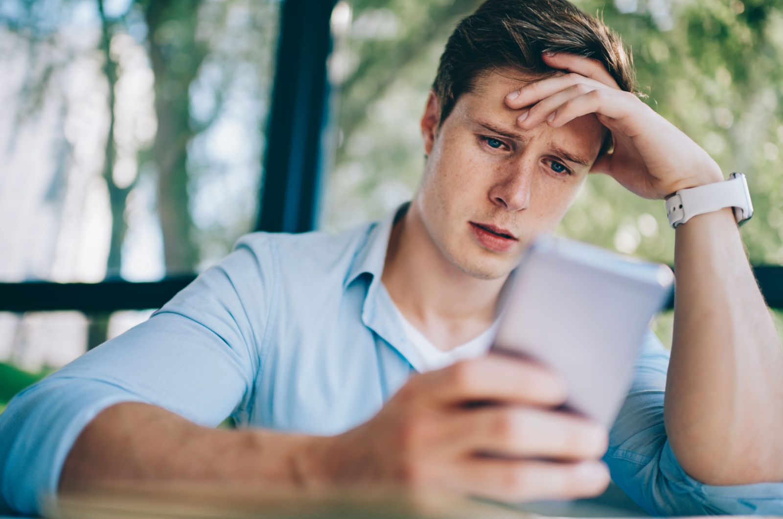 mann sieht aufs handy im schock