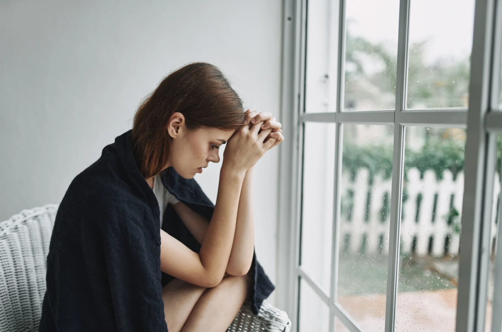 traurige Frau sitzt am Fenster