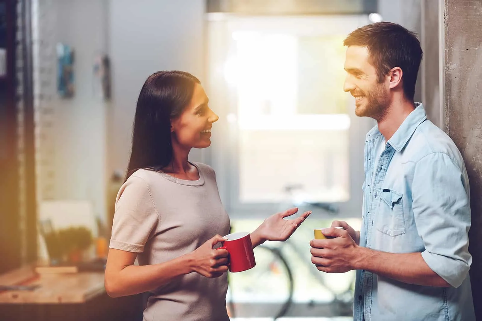 Ein fröhlicher Mann und eine Frau unterhalten sich beim Kaffeetrinken im Stehen