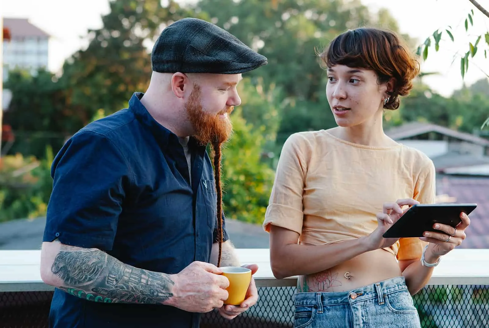 Ein Mann und eine Frau unterhalten sich und benutzen ein Tablet auf einer Terrasse