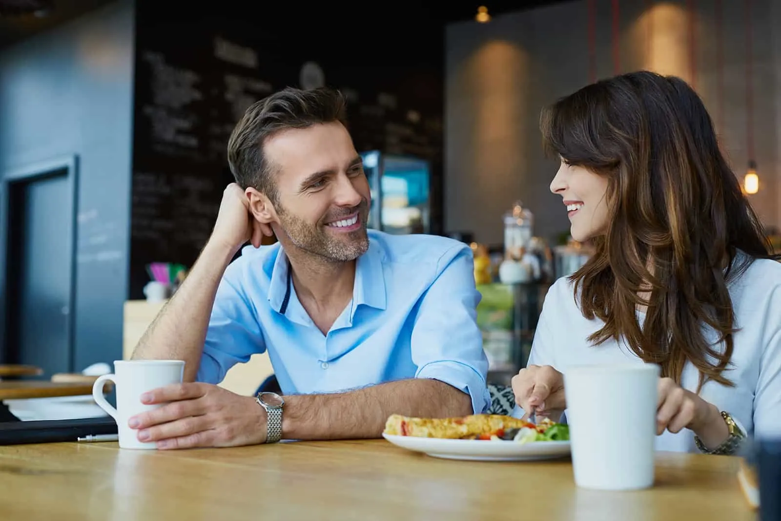 Glückliches Paar, das im Café spricht und zu Mittag isst