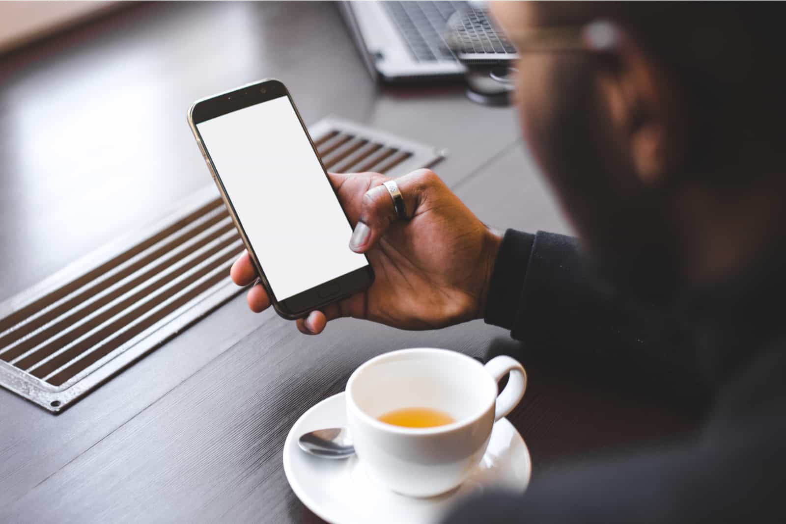 Mann, der Kaffee hält Telefon hält