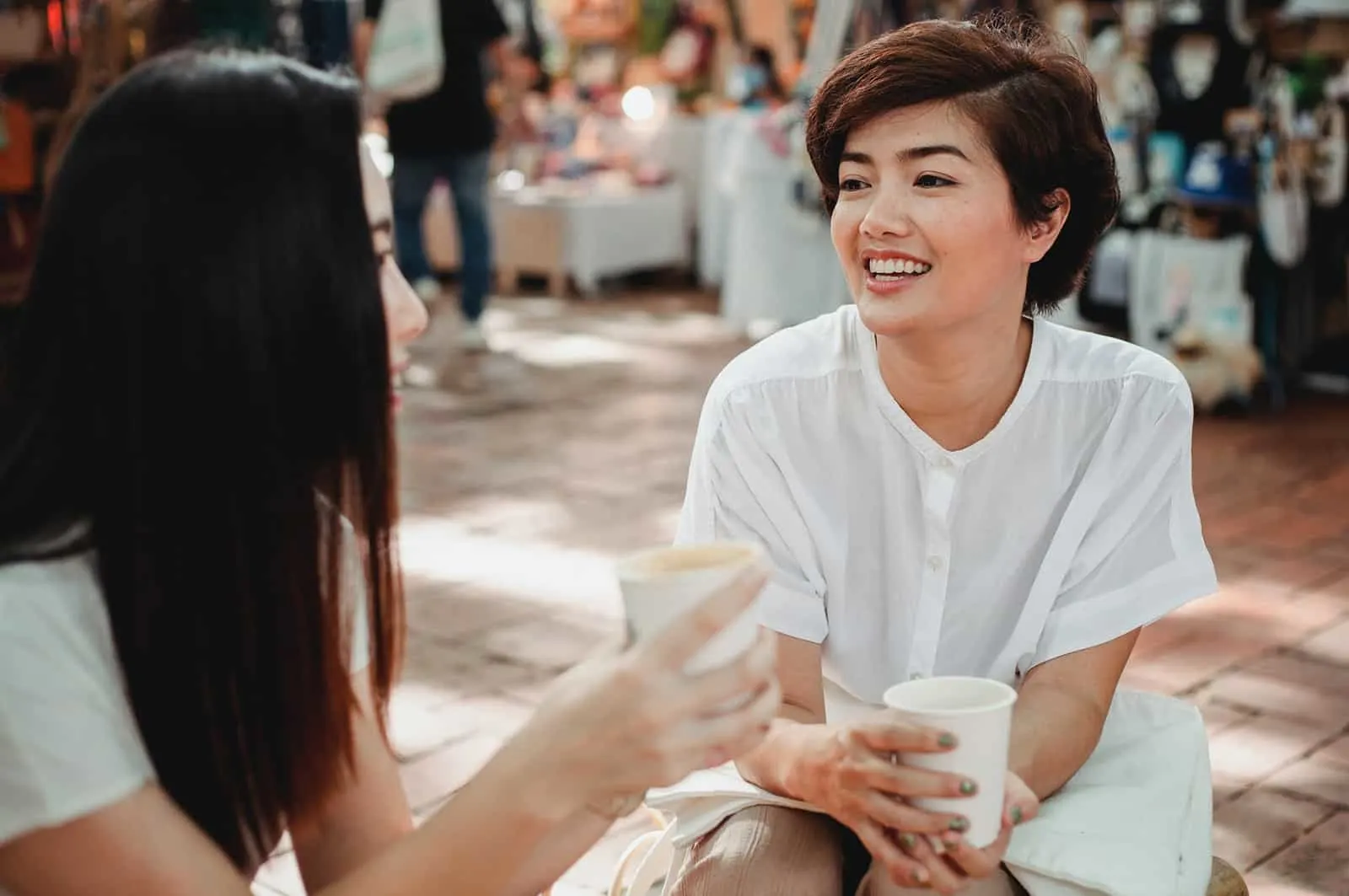 Zwei Frauen unterhalten sich im Straßencafé und trinken Kaffee