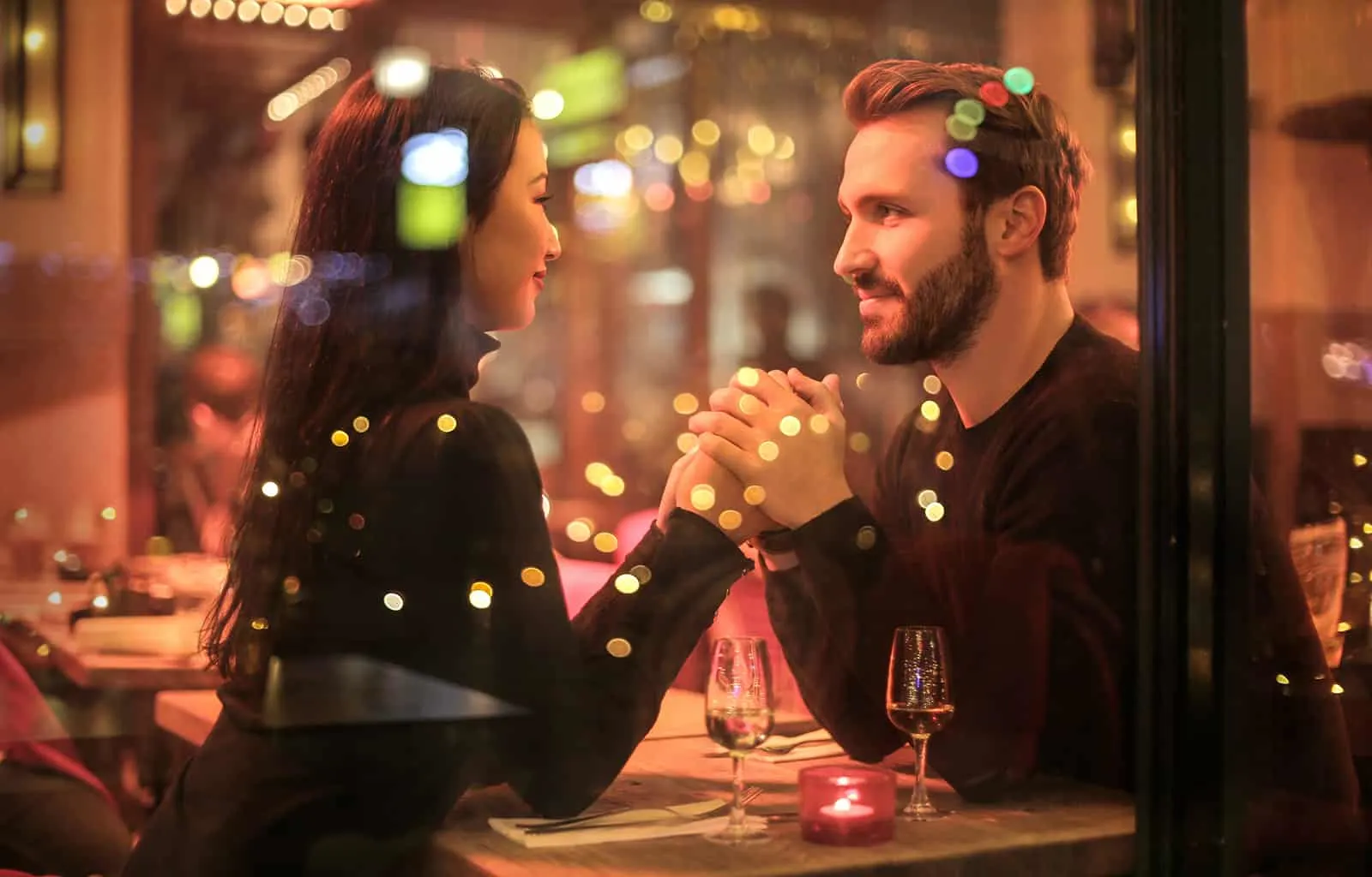 ein liebevolles Paar Händchen haltend in einem romantischen Restaurant
