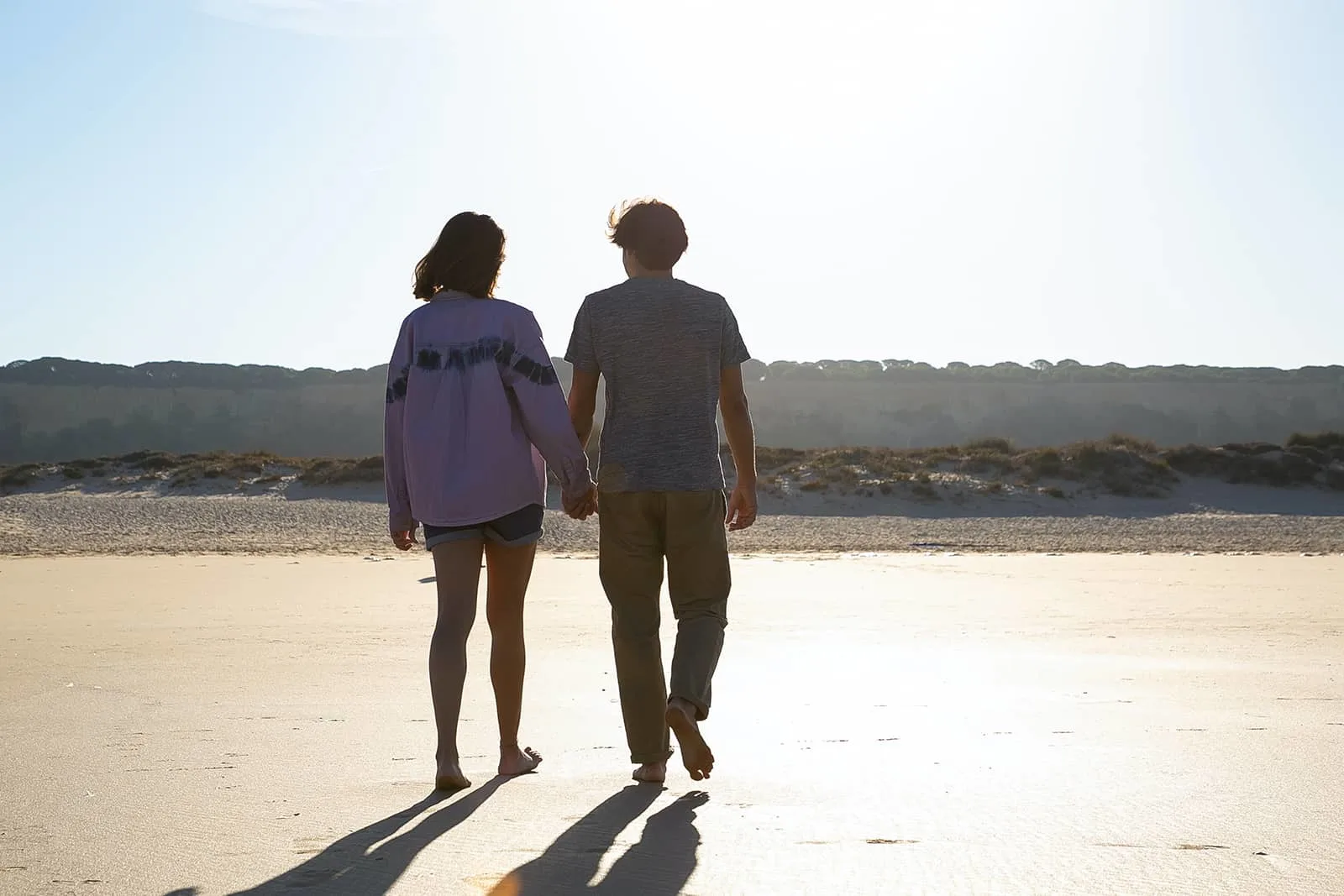 Ein Paar geht am Strand spazieren und hält sich an den Händen